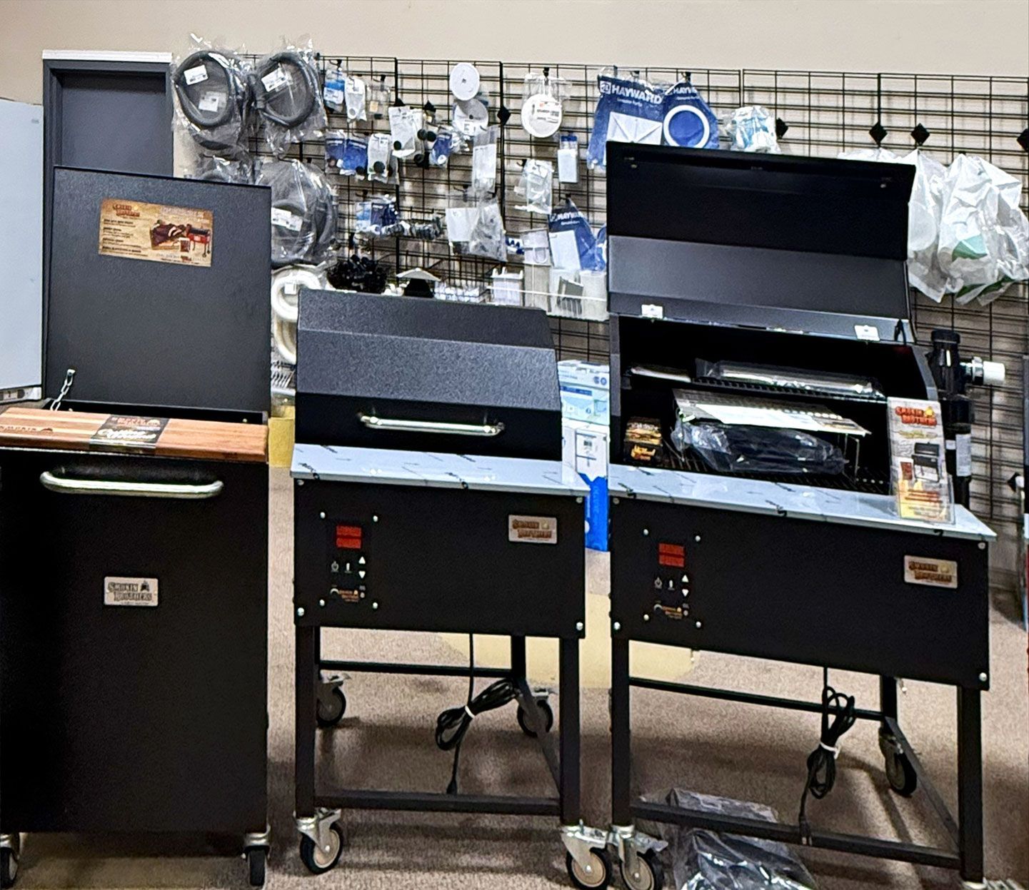 Three black pellet grills on display in a store.