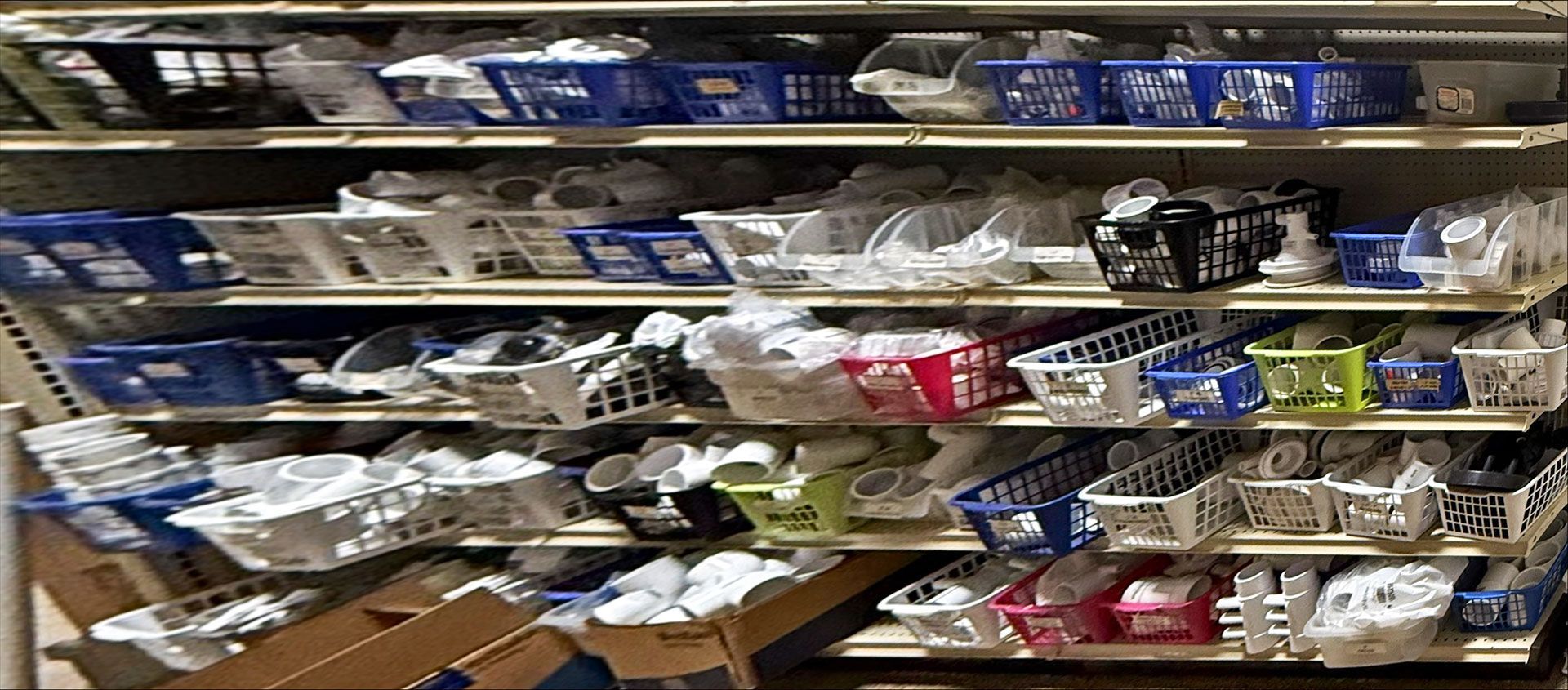 Shelves filled with various bins, baskets, and containers of items in an organized warehouse or storage setting.