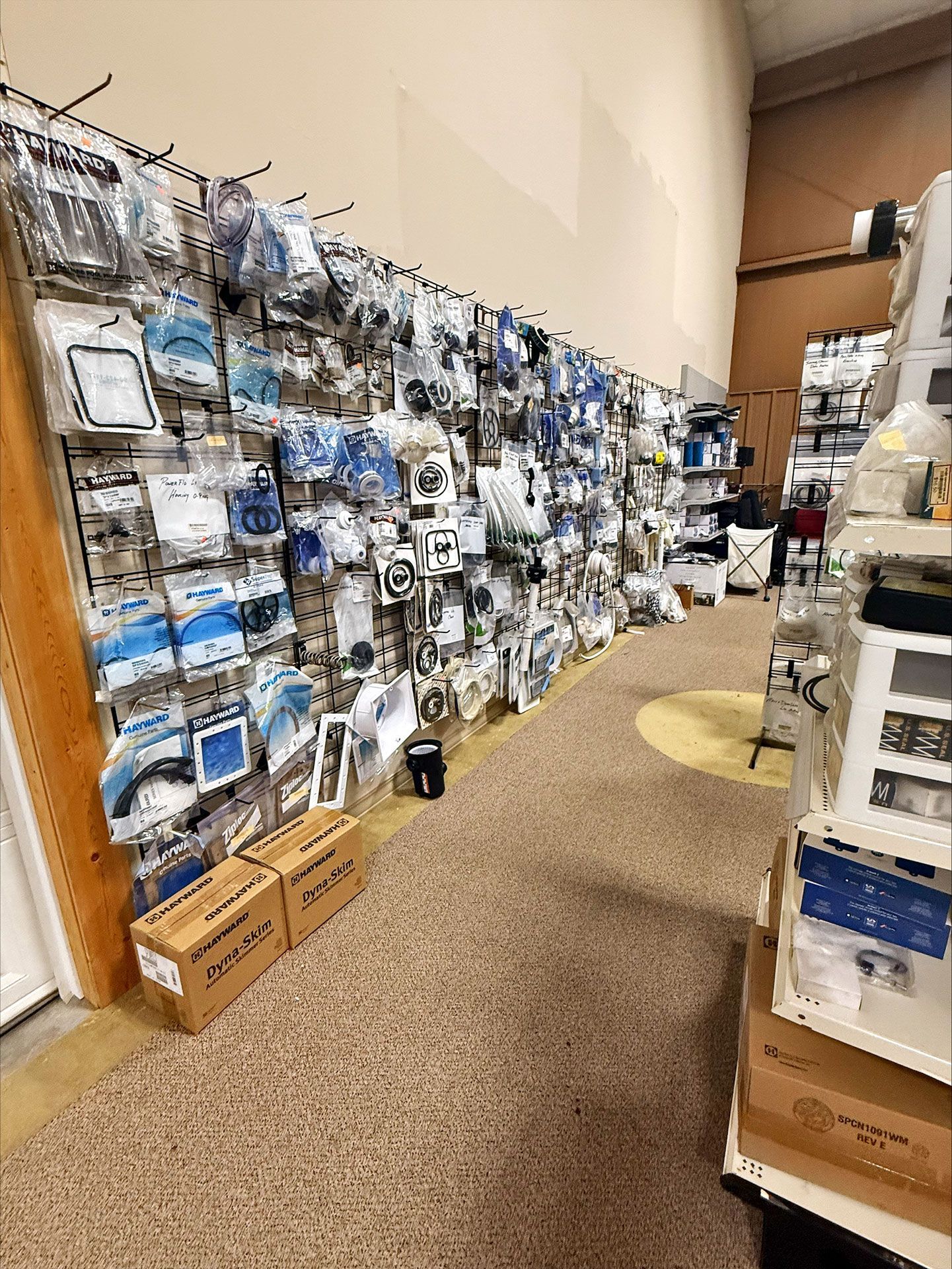 Shelves stocked with packaged electronics in a store. Brown boxes on the floor, wall-mounted displays.