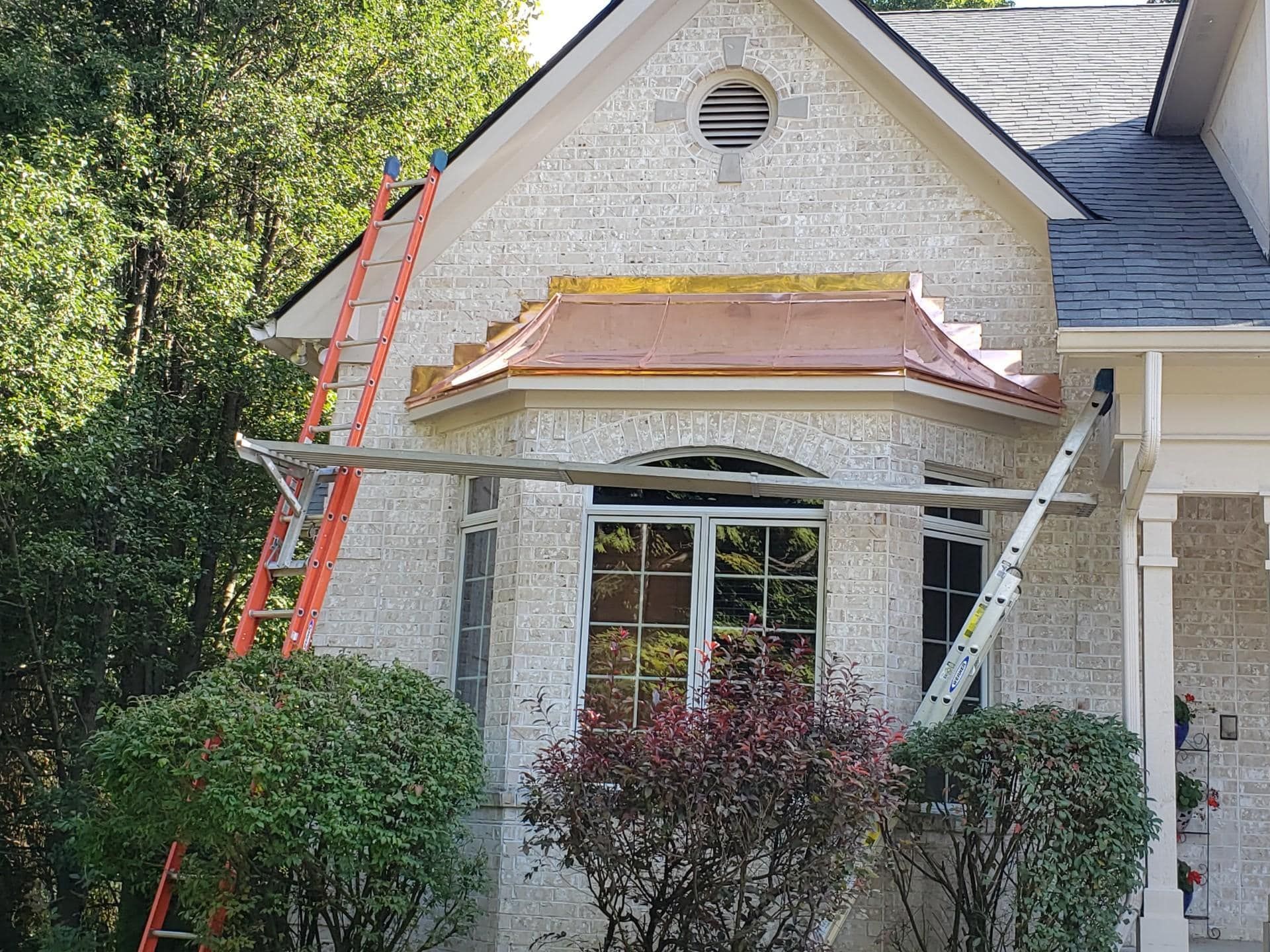 House exterior with a bay window and ladders, possibly under construction.