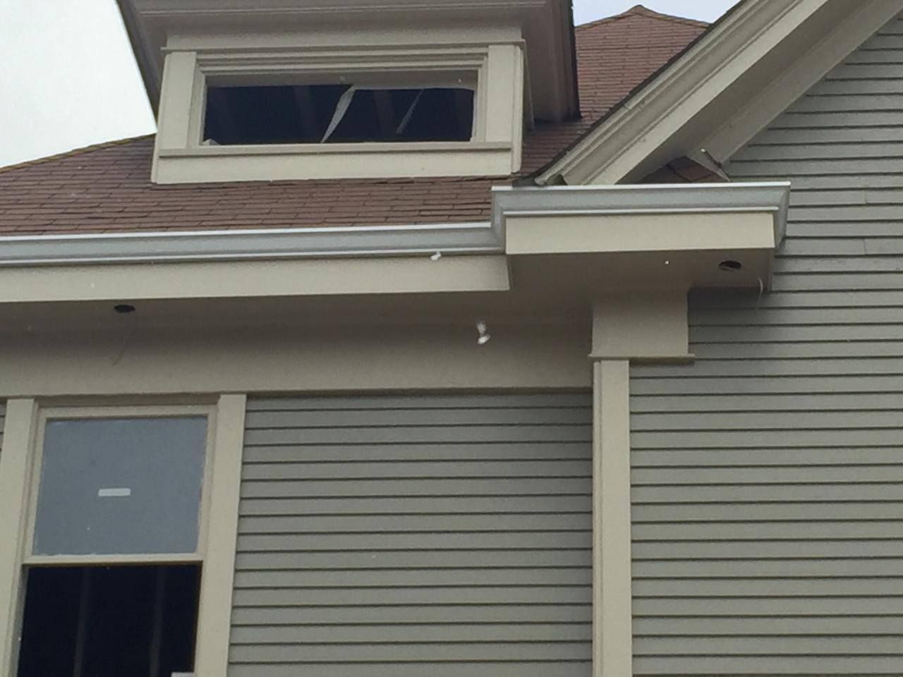 Exterior of a light green house with white trim, brown roof, and a dormer.
