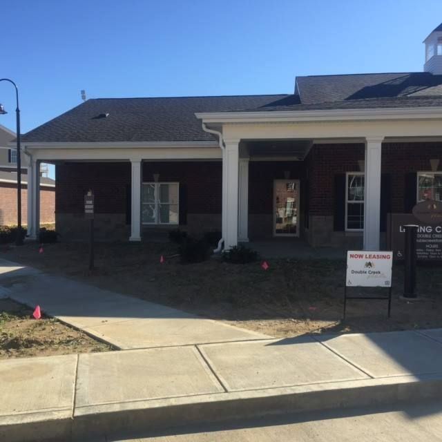 Exterior view of a brick building with white columns and a sidewalk. A 