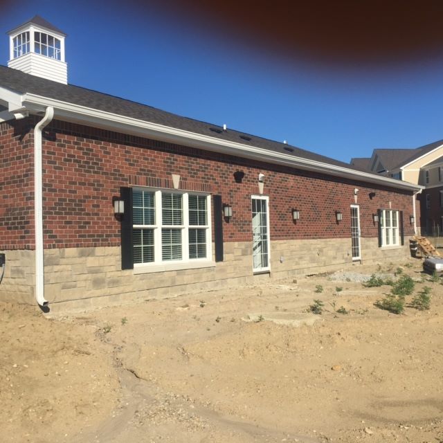Brick building with white trim, a cupola, and windows. Set on a stone base, construction site.