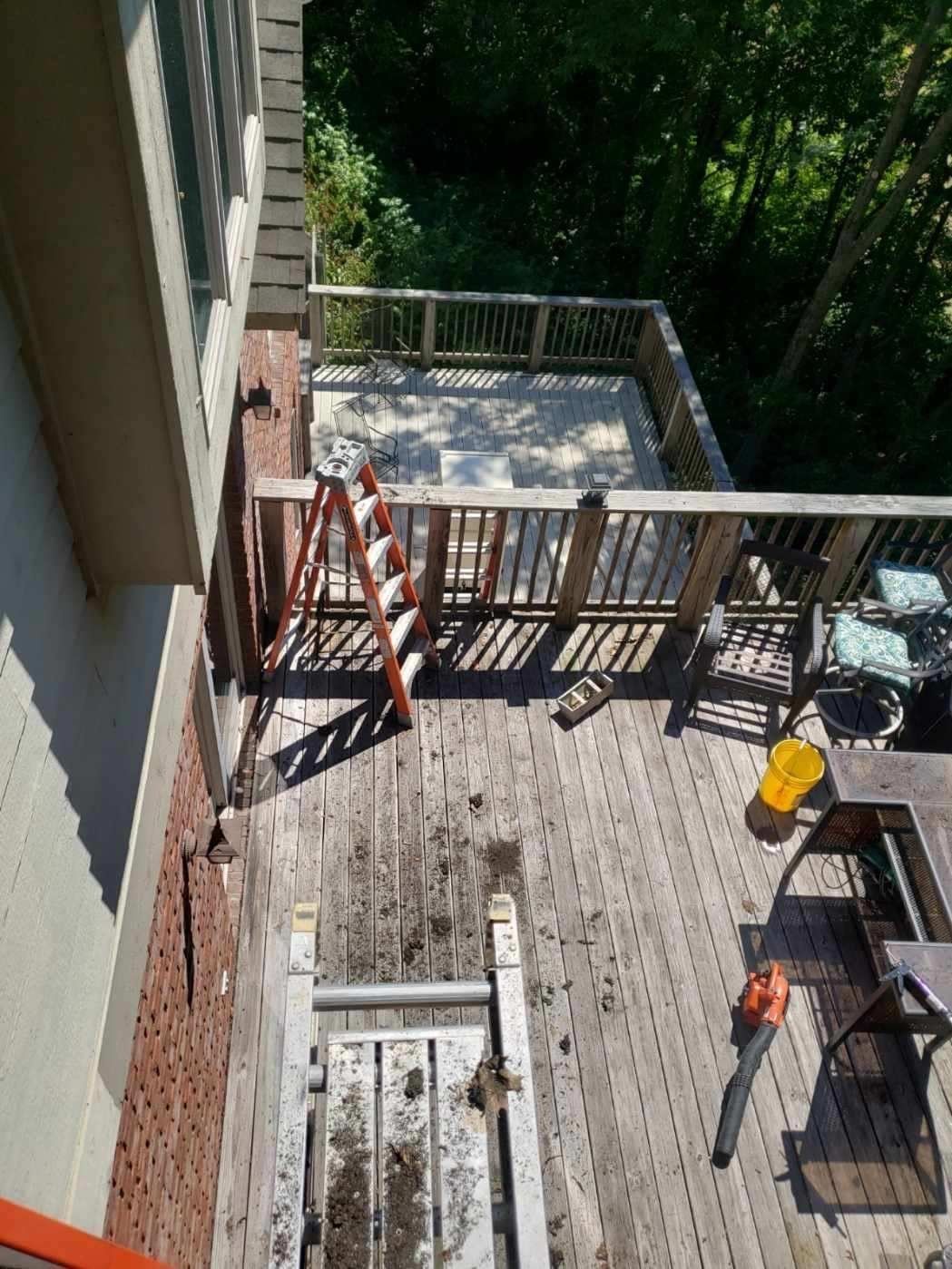 A wooden deck attached to a brick building; a ladder and debris are present, suggesting work in progress.