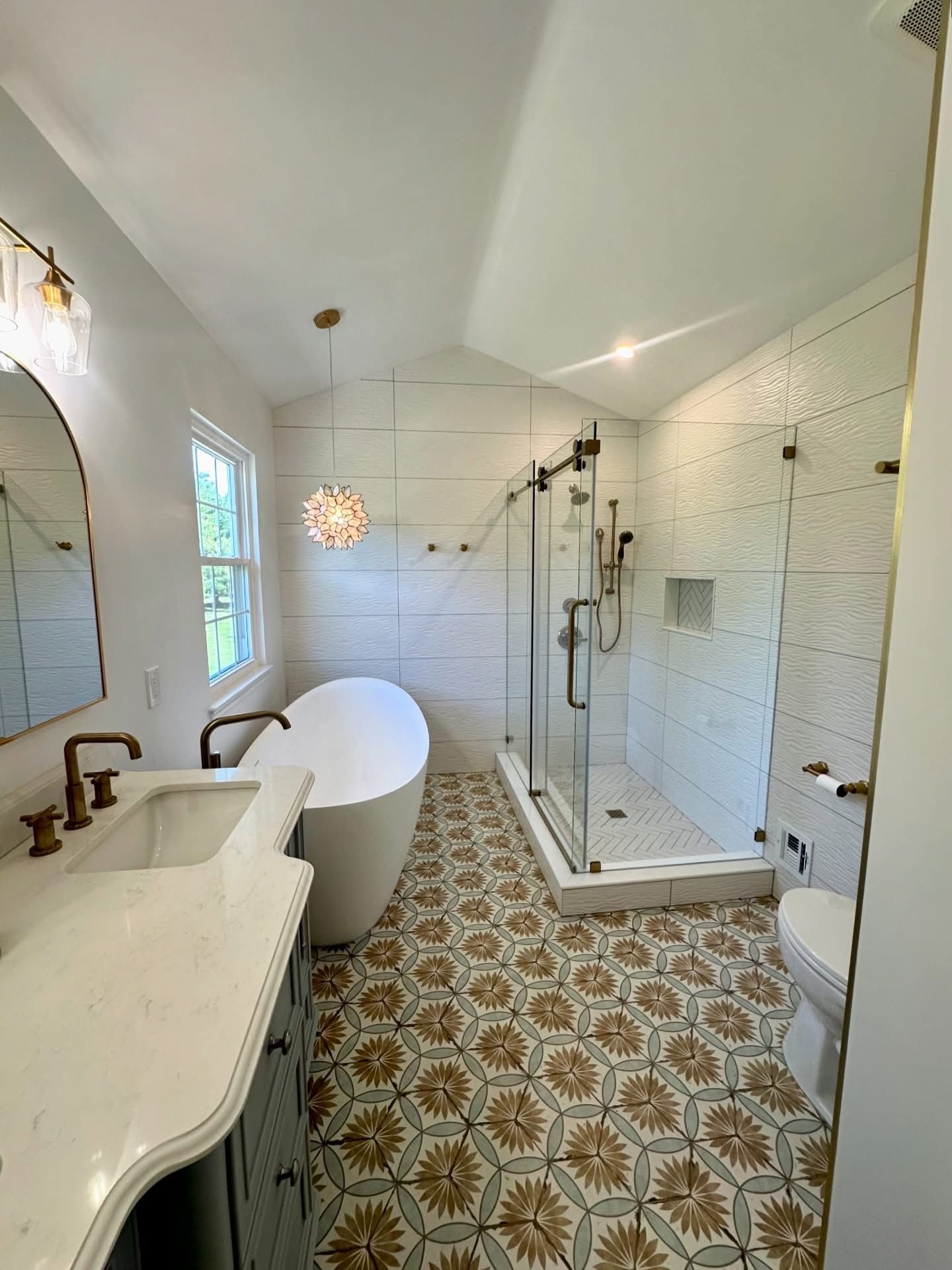 Bright white vintage bathroom with patterned tile floor, clawfoot tub, glass shower, and double sink.
