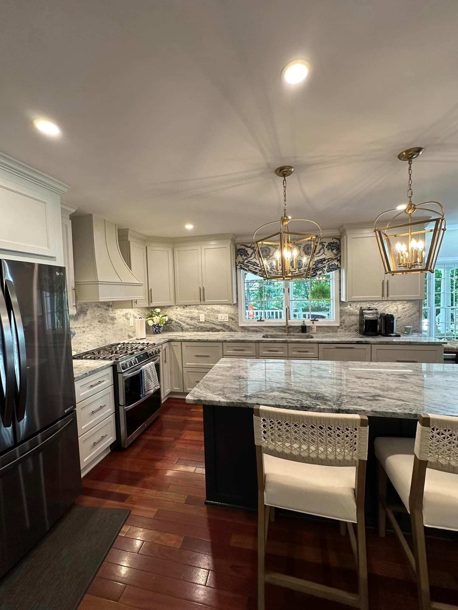 Modern kitchen with granite island, white cabinets, stainless appliances, and two pendant lights