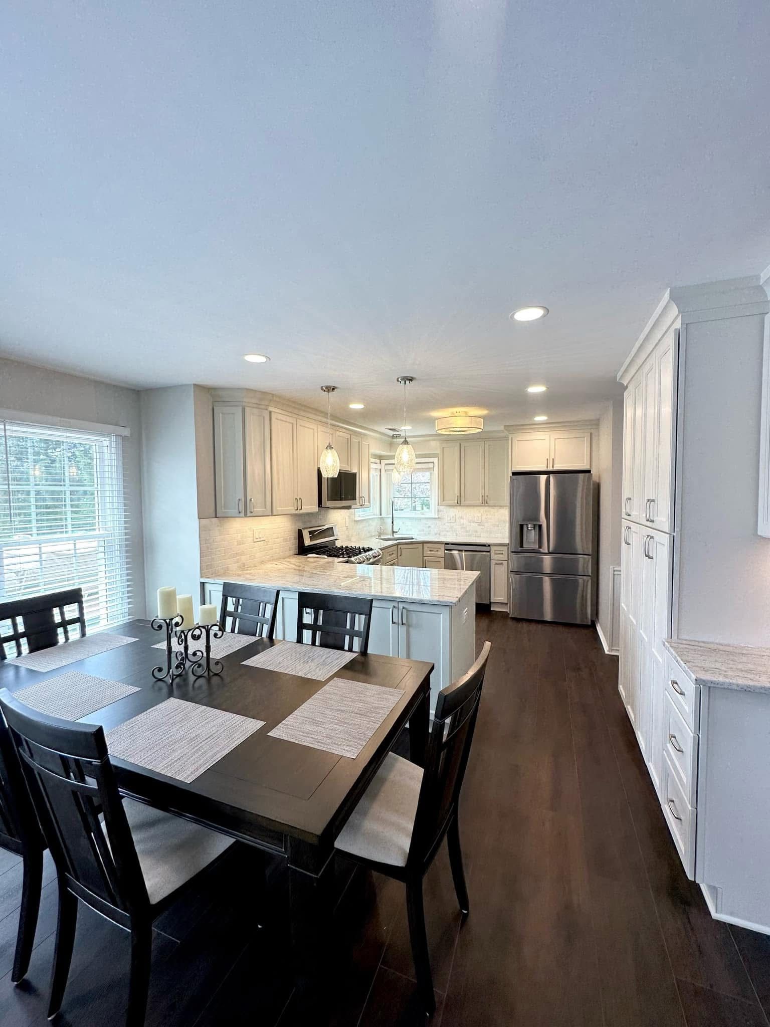 Dining area and kitchen with black table and chairs, stainless steel fridge, and light wood floors
