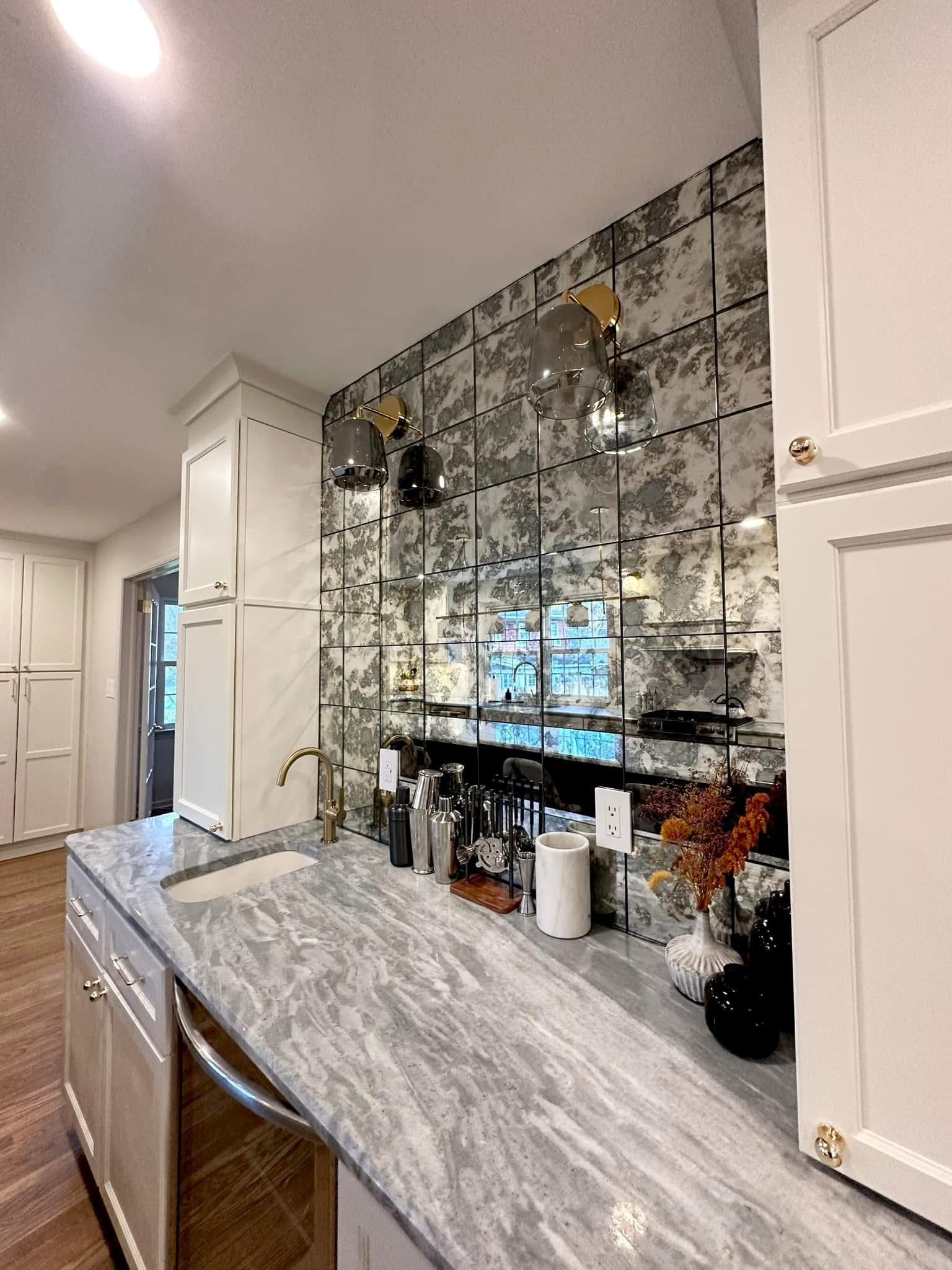 Kitchen with marble countertop, mirrored backsplash, and built-in coffee station under white cabinets