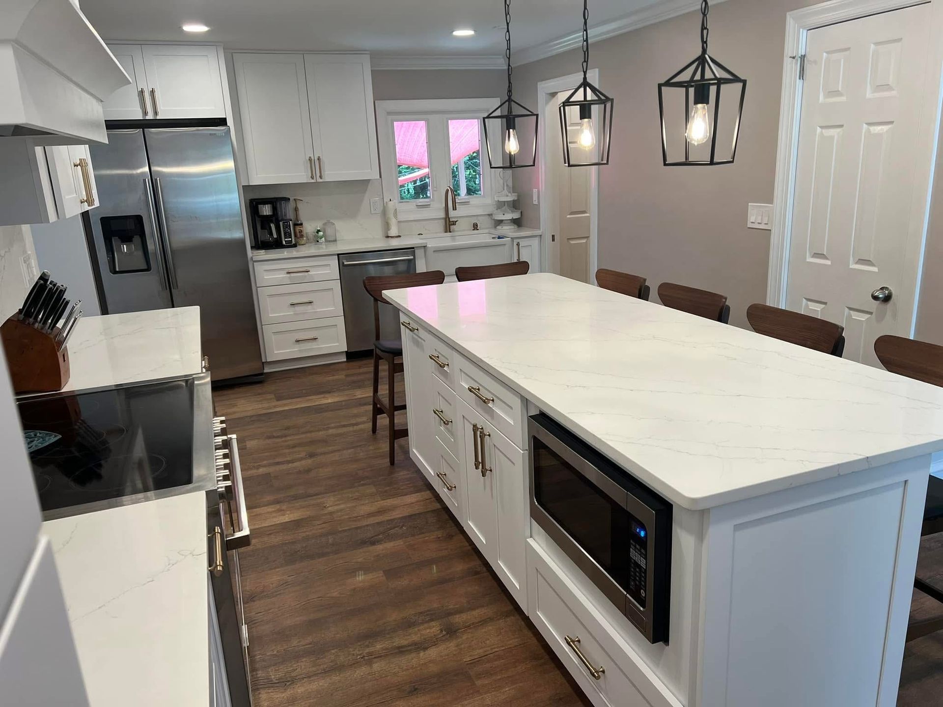 Modern kitchen with white island, stainless appliances, gray cabinets, and wood floors