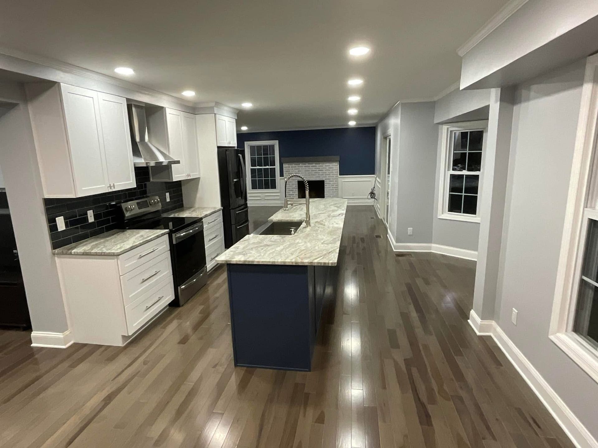 Bright modern kitchen with white cabinets, island, and hardwood floors in an open living space