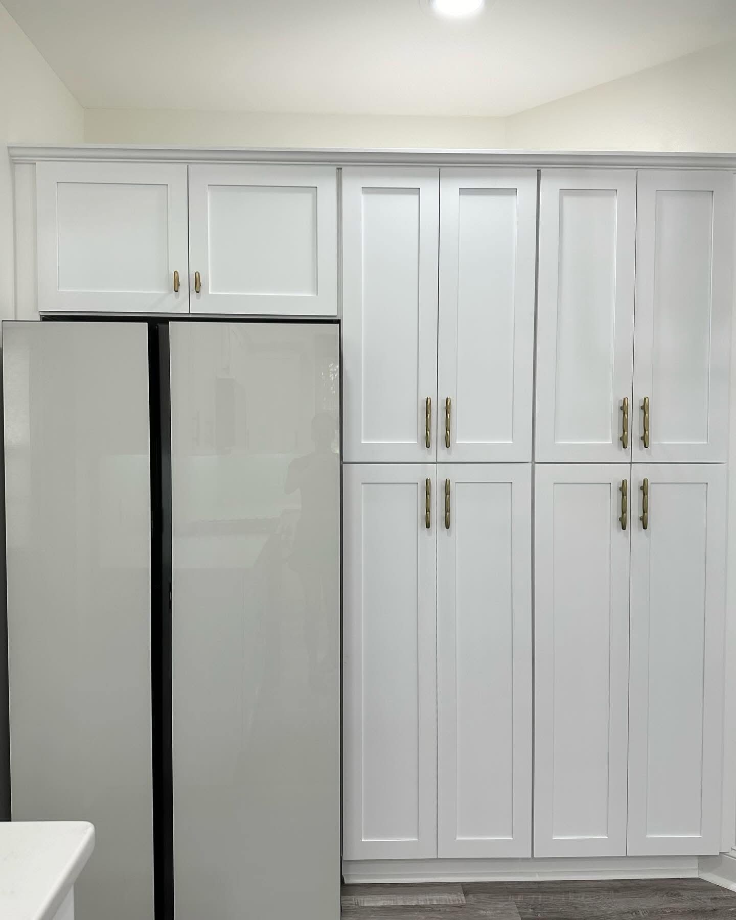 White kitchen cabinets and a stainless steel refrigerator in a bright kitchen.