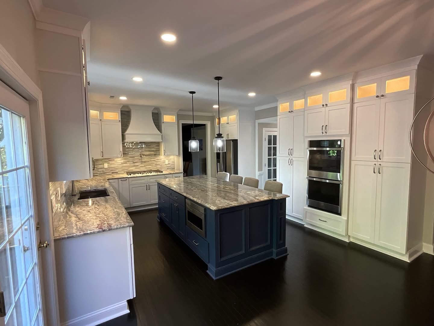 Bright modern kitchen with white cabinets, granite countertops, and a large navy island.