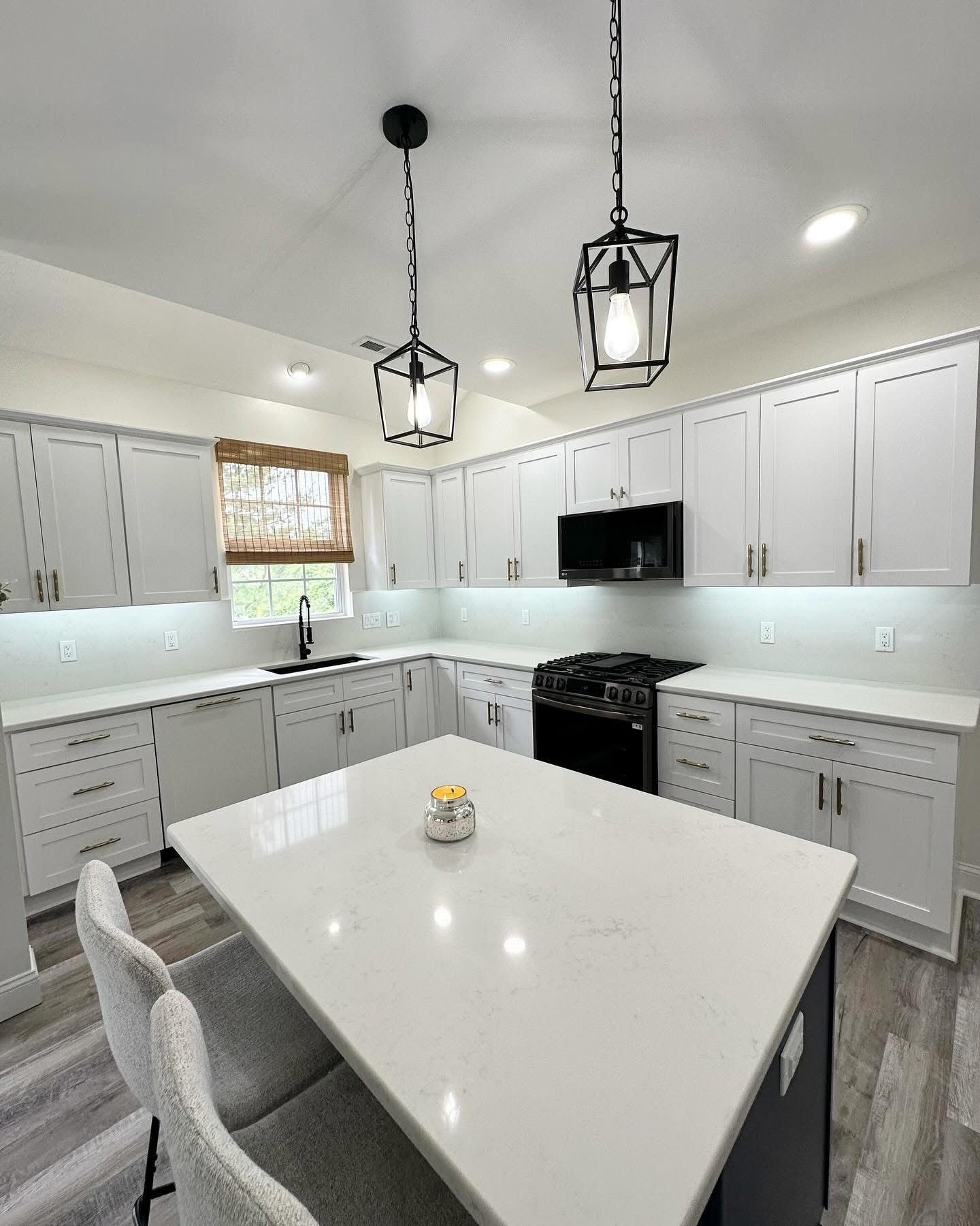 Bright white modern kitchen with island, pendant lights, and stainless steel appliances