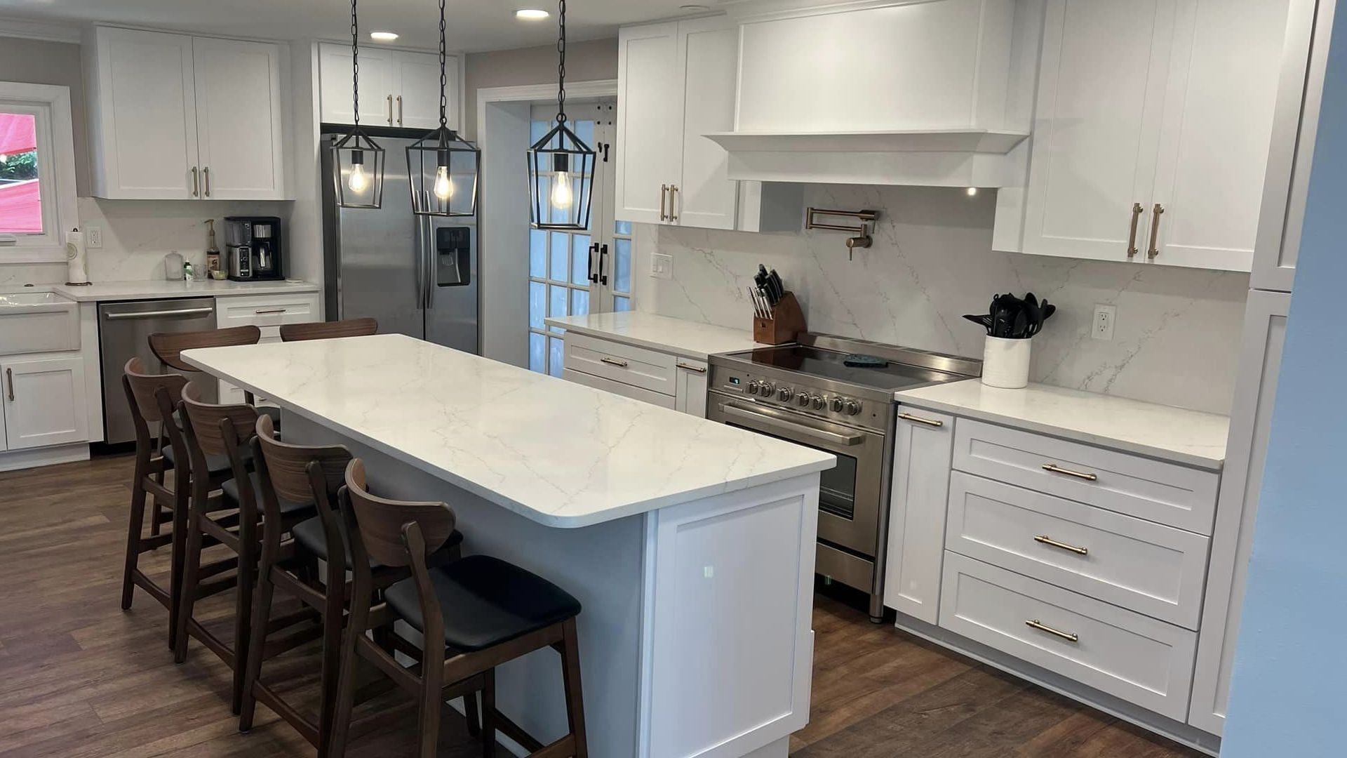 Bright modern kitchen with white cabinets, marble island, and barstools, viewed from the dining area