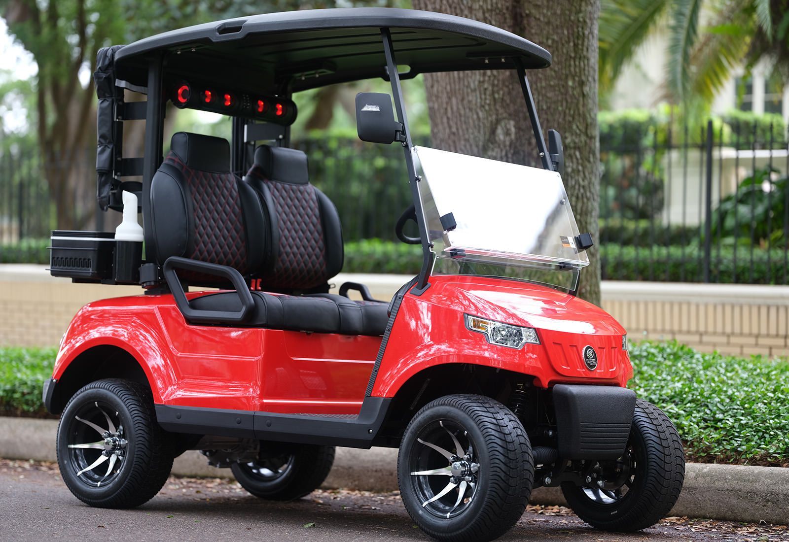 White golf carts parked in a row, with canopies, on a sunny day.