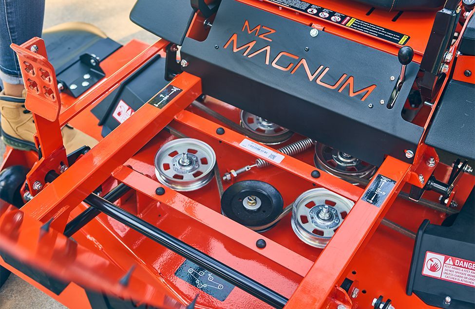 Orange riding lawn mower deck showing pulleys and belts. 