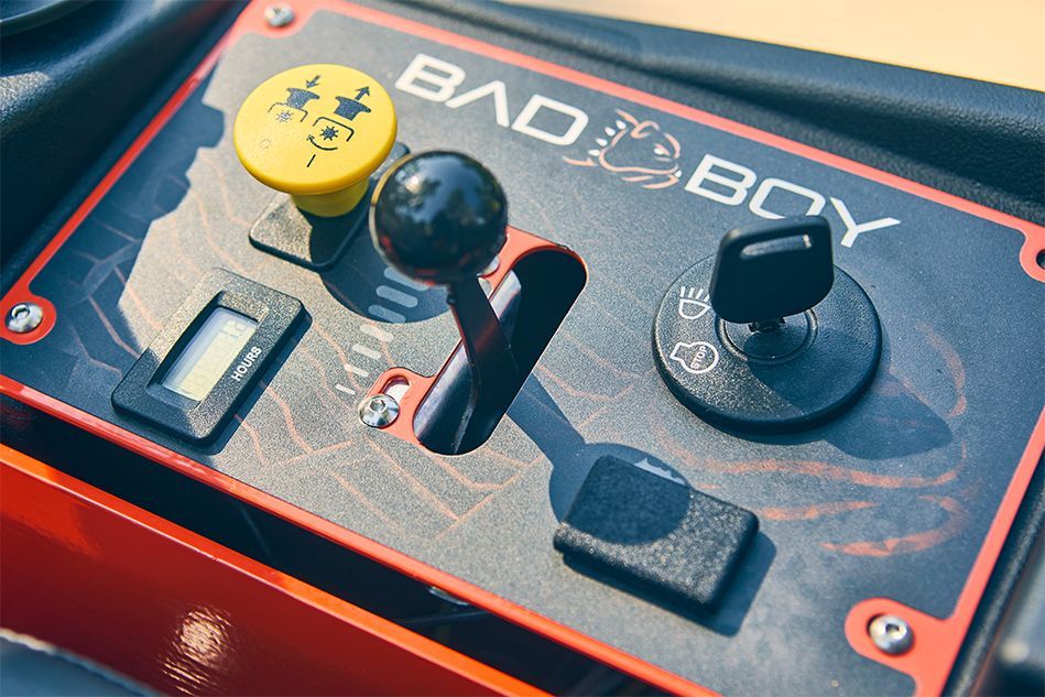 Control panel of a Bad Boy lawnmower: black and red, key, lever, display screen, yellow button.