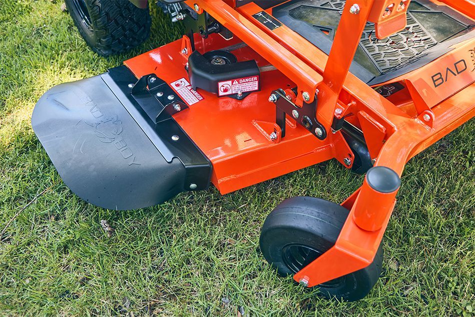Orange and black zero-turn mower deck on grass.