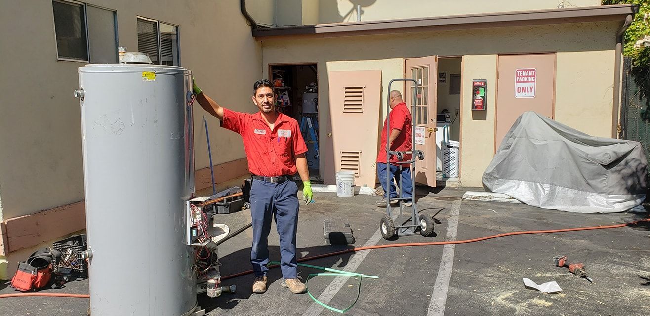 Person in red shirt stands beside a large white tank in an outdoor utility area.