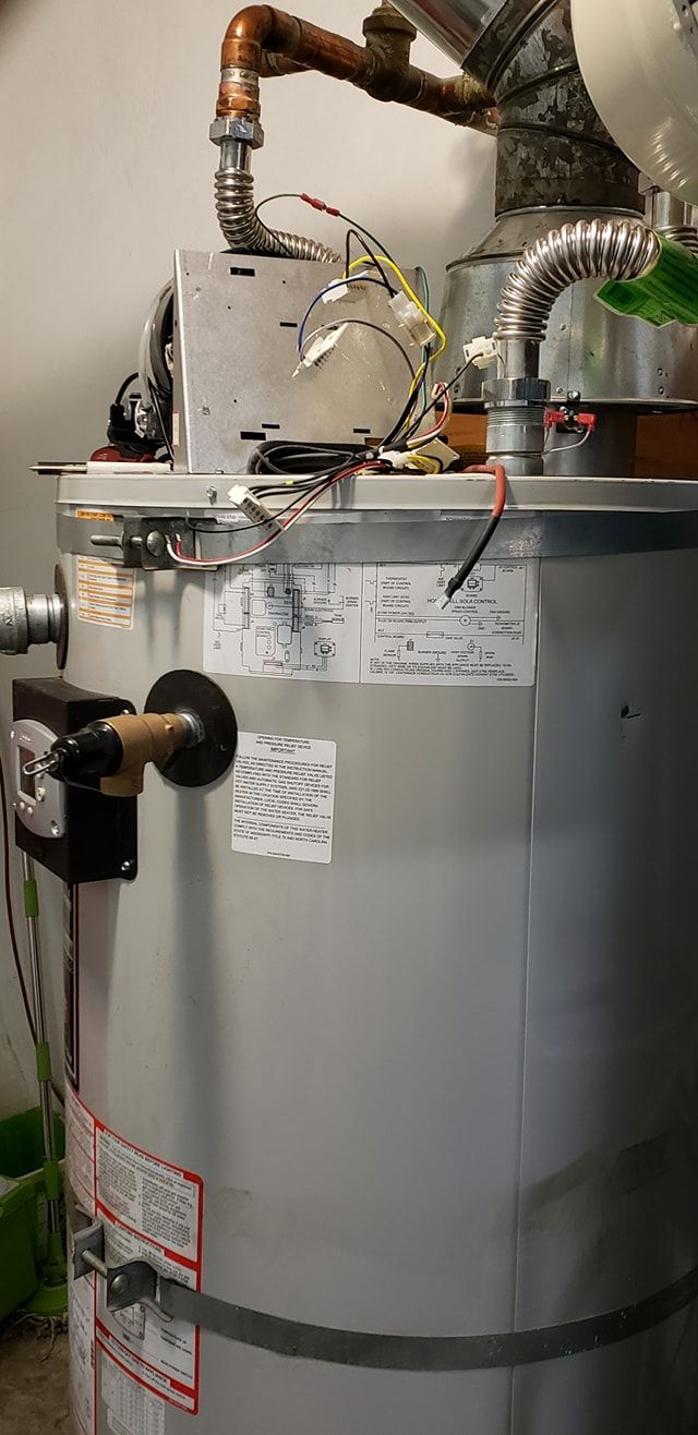 Large gray water heater with pipes and wires in a utility room