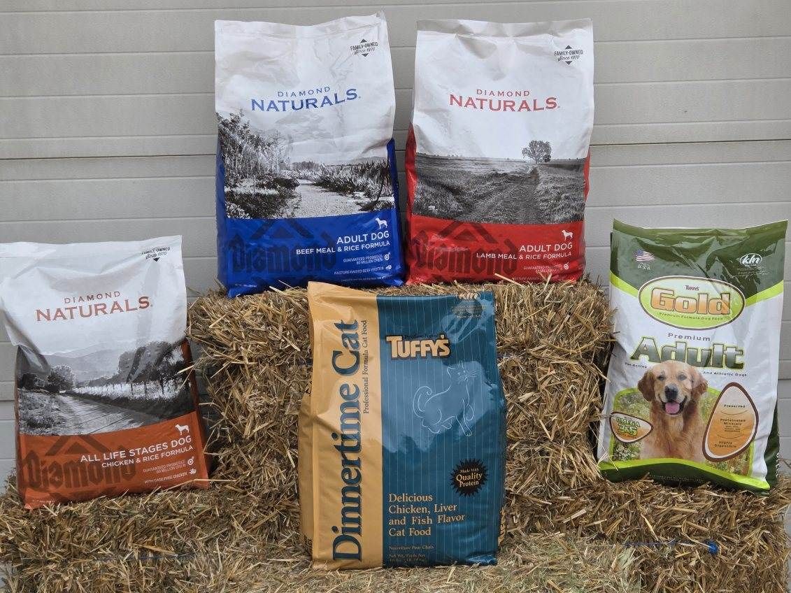 A bunch of bags of dog food are sitting on top of a pile of hay