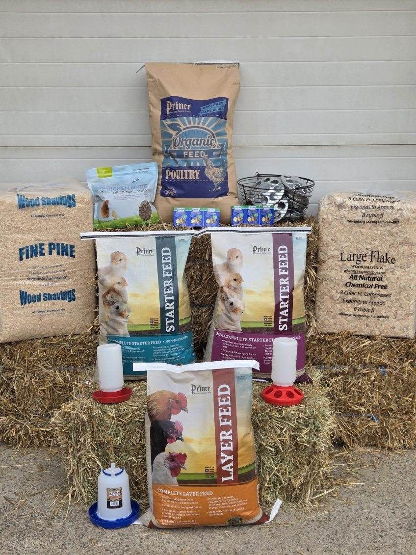 A bunch of bags of bbq pellets are sitting on top of a bale of hay