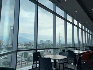 A restaurant with tables and chairs in front of a large window with a view of the city.