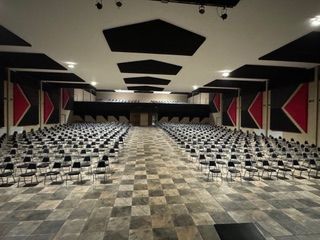 A large auditorium with rows of chairs and a checkered floor.