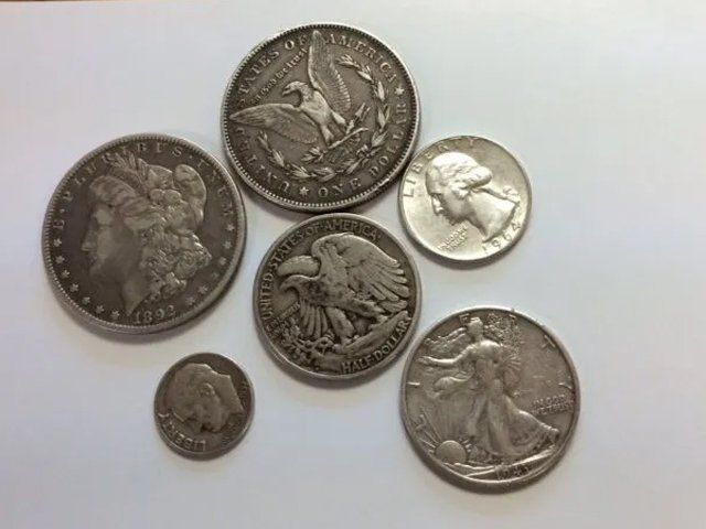 Silver coins of various sizes and designs on a white surface.