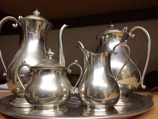 Silver tea set on a tray: tea pot, creamer, sugar bowl, and coffee pot.