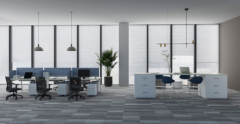 Modern open office with desks, chairs, pendant lights, and large windows overlooking a city skyline.