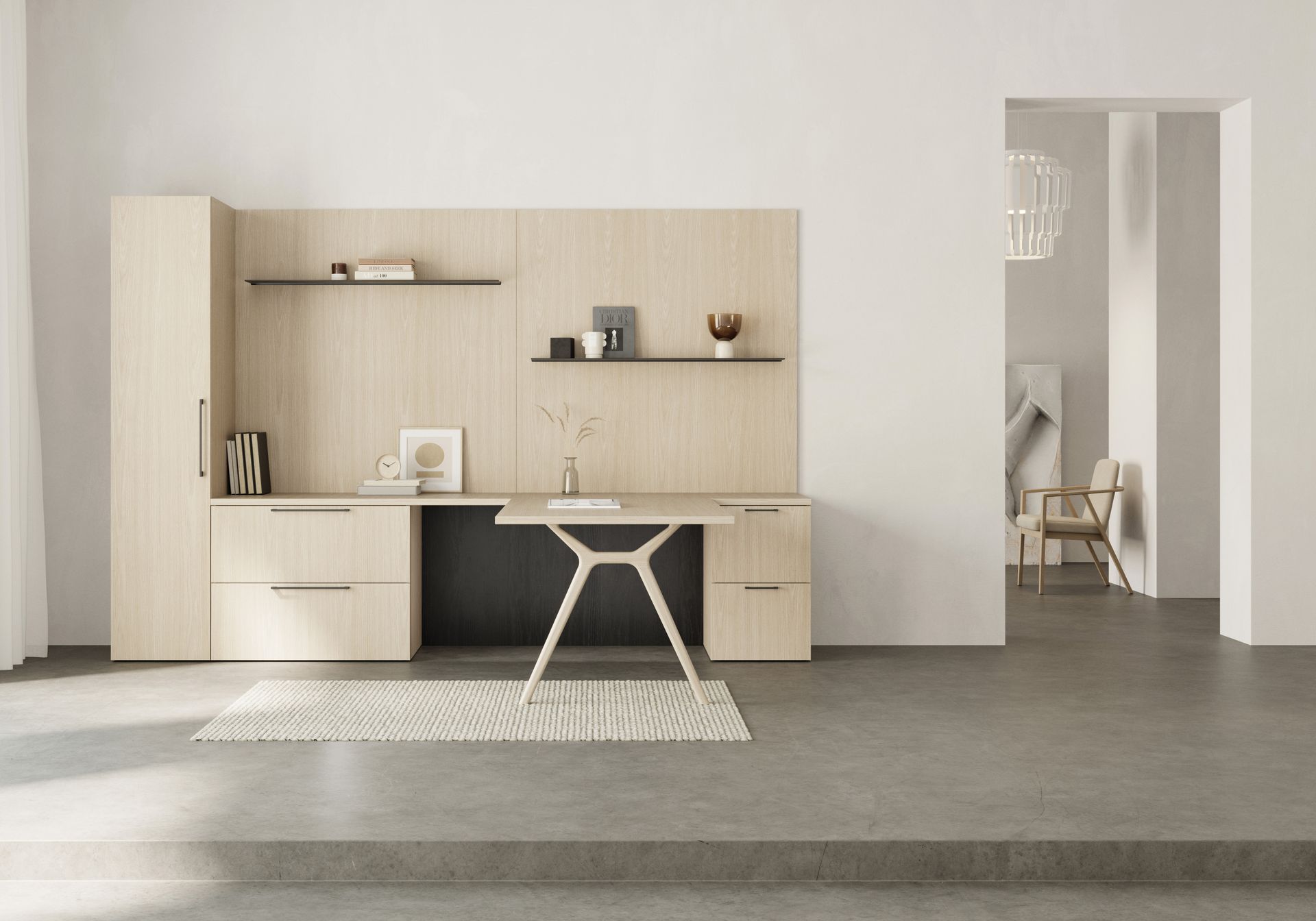 Minimalist home office desk in a light wood wall unit, with shelves and a chair on a gray floor.