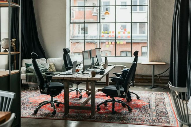 Modern office meeting room with black chairs, large table, and tall windows