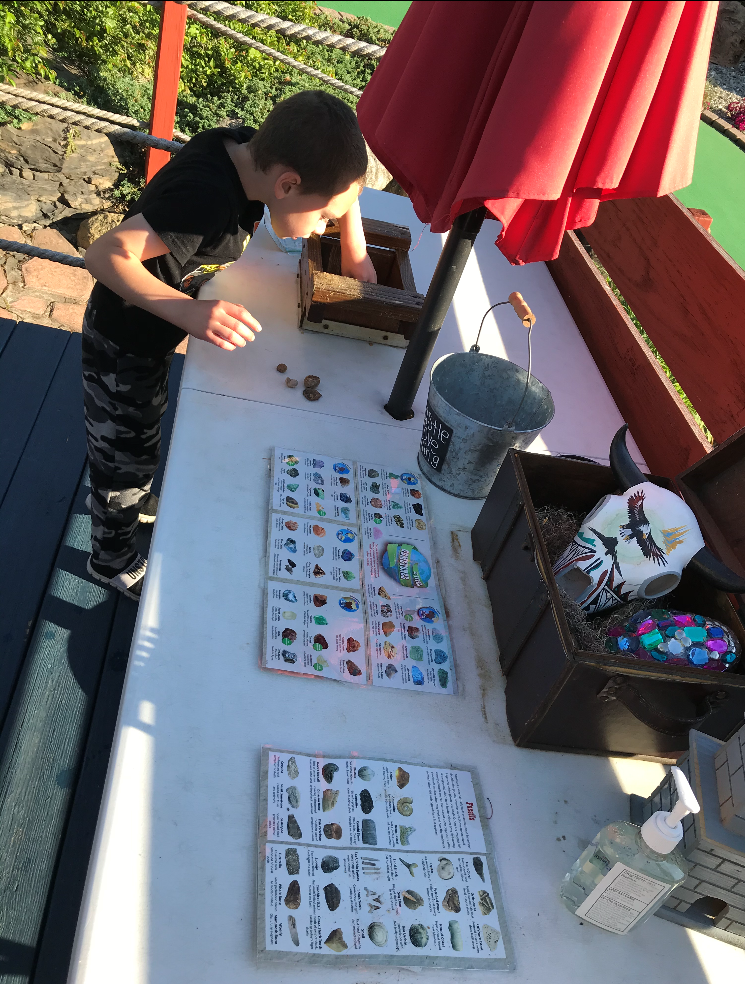 A boy is playing a game on a table with a red umbrella