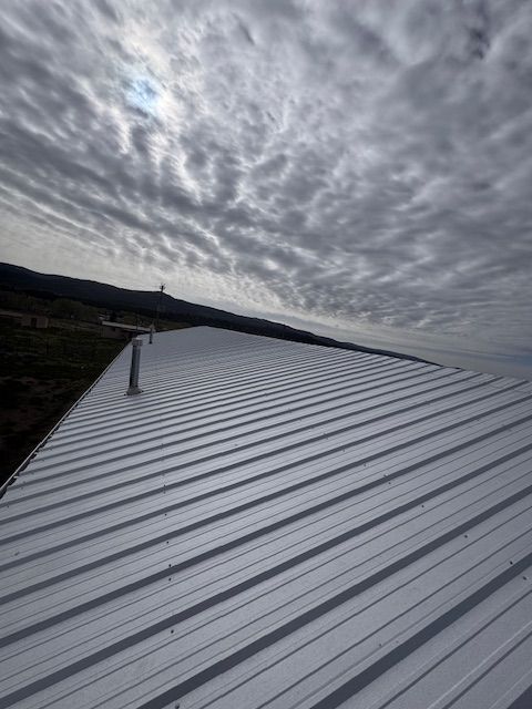 White metal roof under a cloudy sky, with distant hills along the horizon