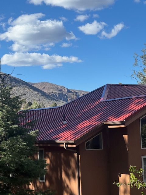 Red-roofed house with mountains and blue sky with clouds in the background