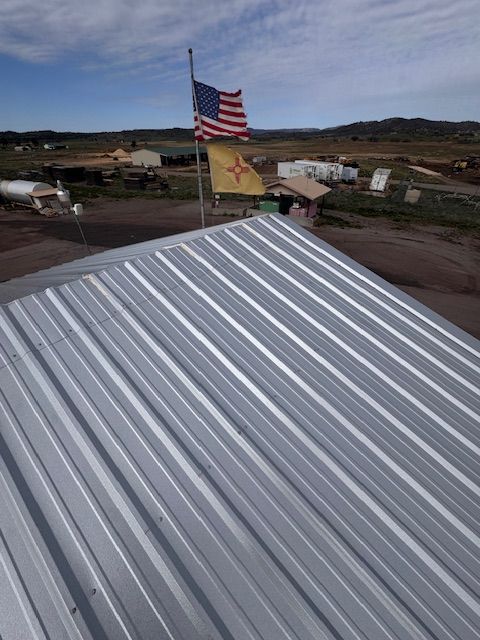 Silver metal roof in foreground with an American flag flying over a rural landscape at dusk