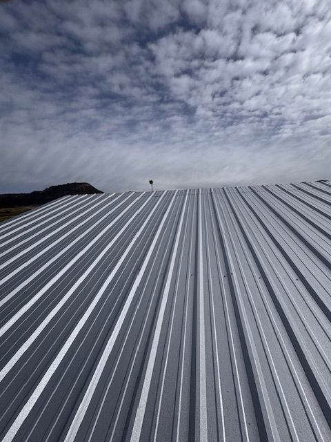 Metal rooftop with white and gray stripes under a cloudy sky
