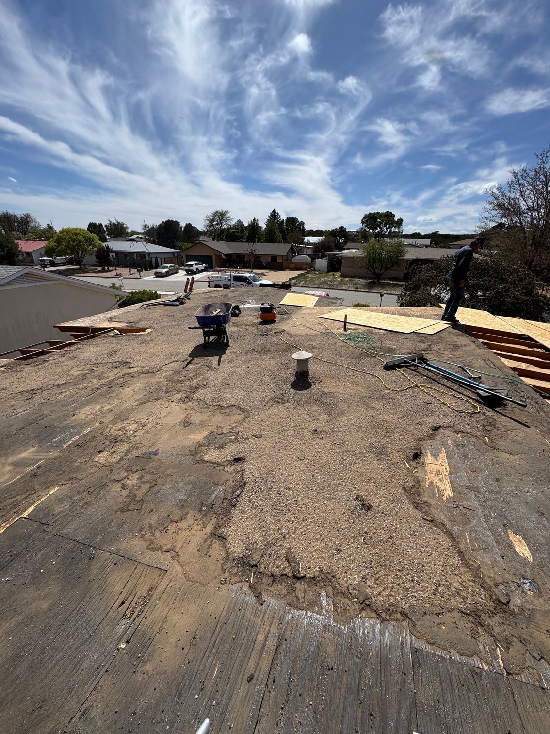 Construction site with dirt path, scattered materials, and a small tractor under a cloudy blue sky