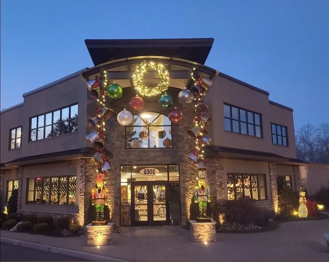 A tan building decorated for Christmas with a large wreath, giant ornaments, and two nutcracker statues by the entrance.