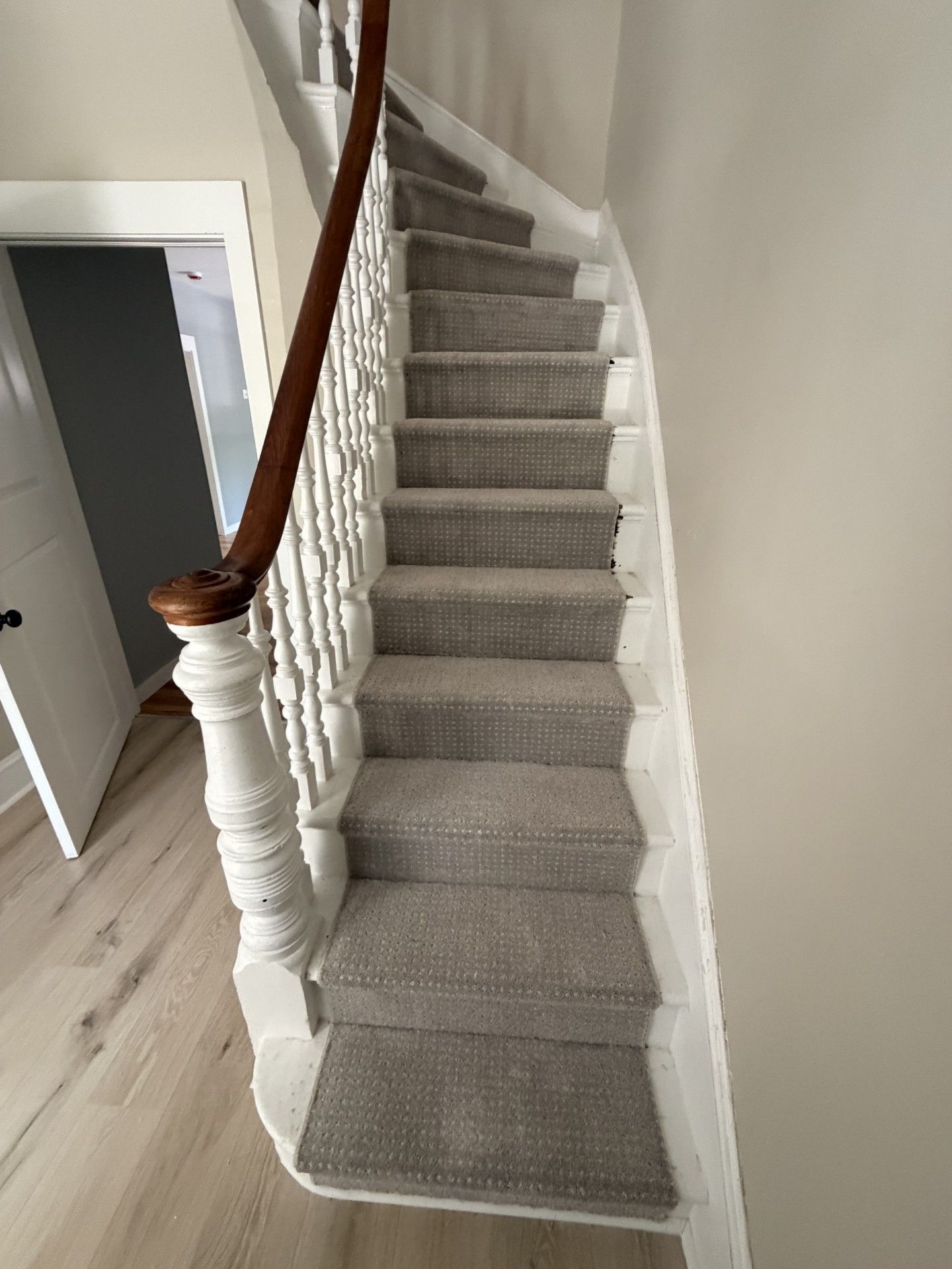 Carpeted staircase with white balusters and a dark wooden handrail in a home interior.