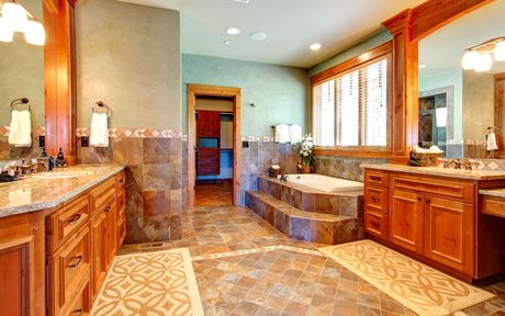 A large bathroom with two sinks, a tub, and two mirrors