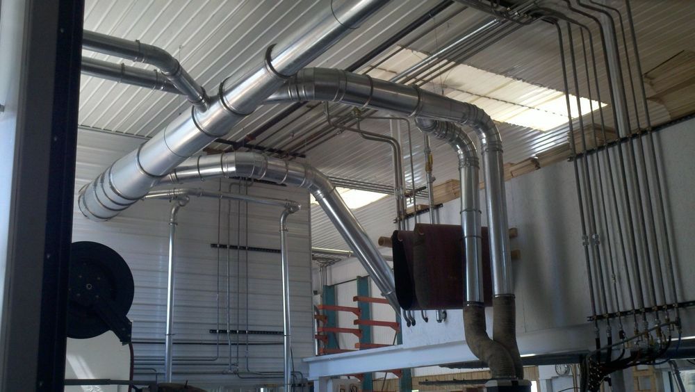 There are many pipes hanging from the ceiling of a building.