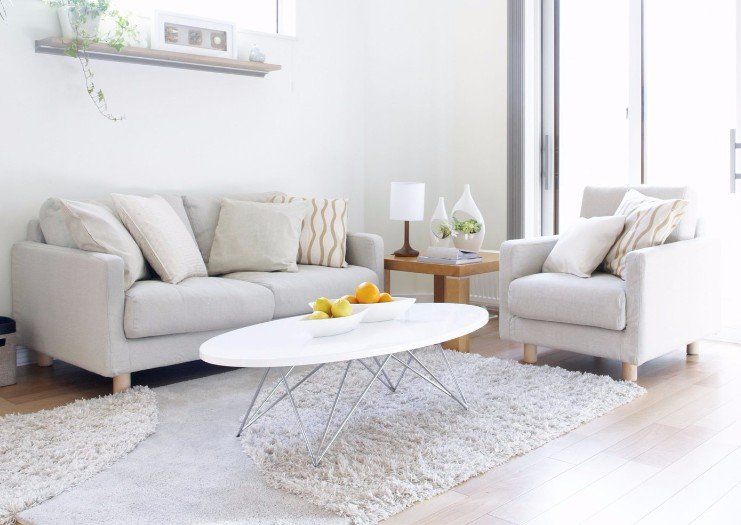 A living room with a couch , chair , coffee table and rug.
