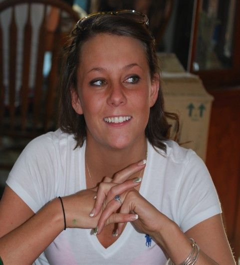 A woman wearing sunglasses and a white shirt smiles for the camera
