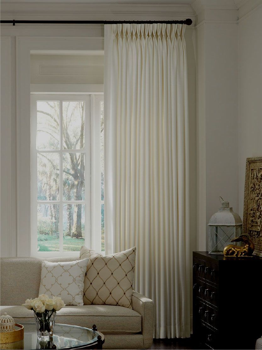 A living room with a couch , table , curtains and a window.
