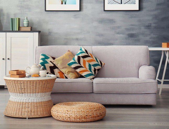 A living room with a couch , coffee table , and wicker ottoman.