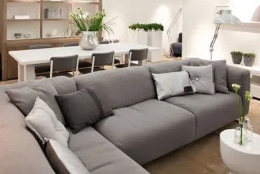 A living room with a large grey couch and a white table.