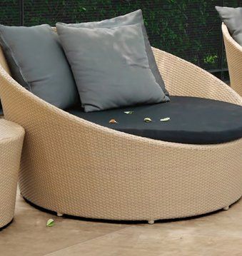 A round wicker chair with two pillows on it