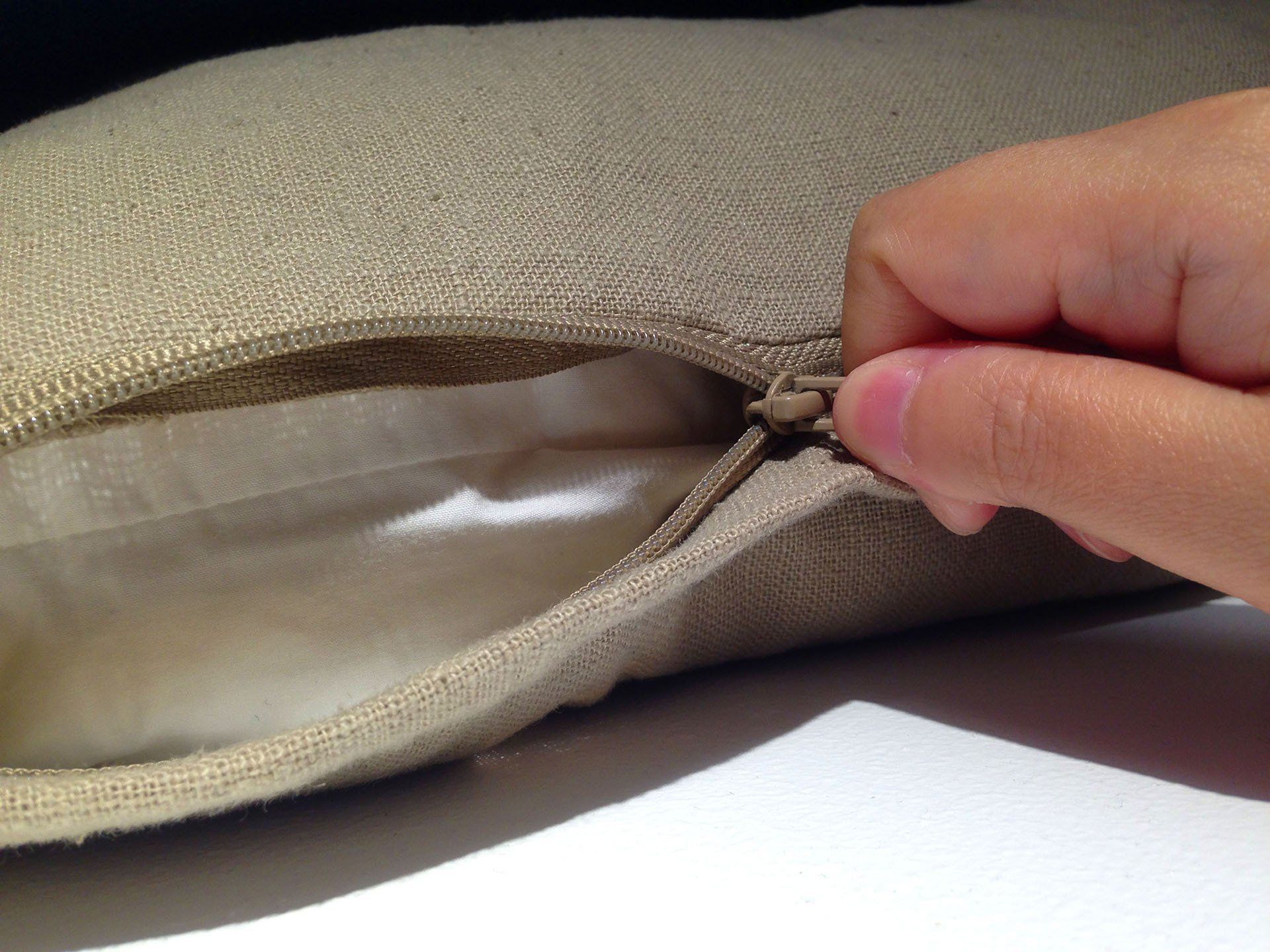 A person is opening a zipper on a pillow